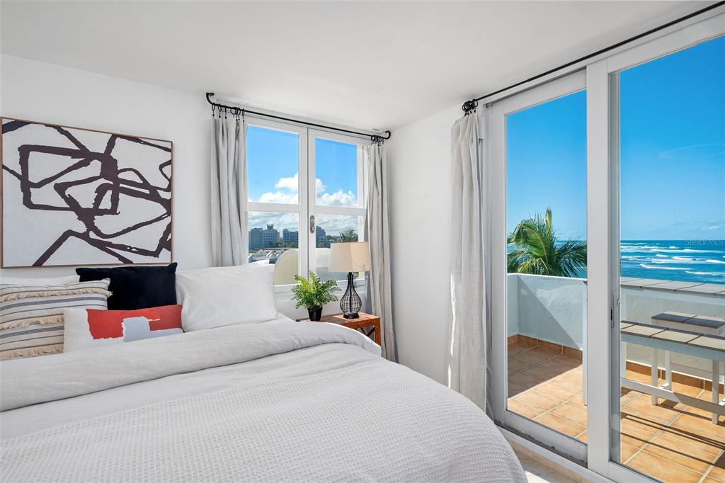 A bedroom features a bed, a window, and a sliding door opening to an oceanfront balcony — Villas de COSTA DORADA UNIT H3, DORADO, PR