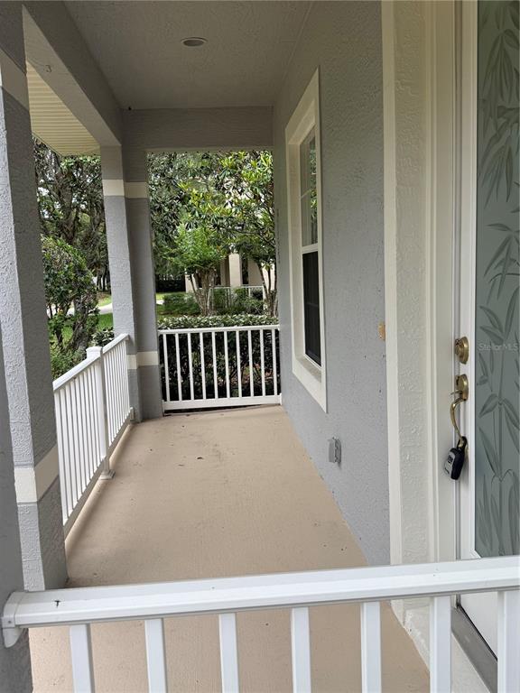 A covered front porch features a white railing, a light-colored floor, and a glass-paneled door — 3132 CONNEMARA DRIVE, ORMOND BEACH, FL