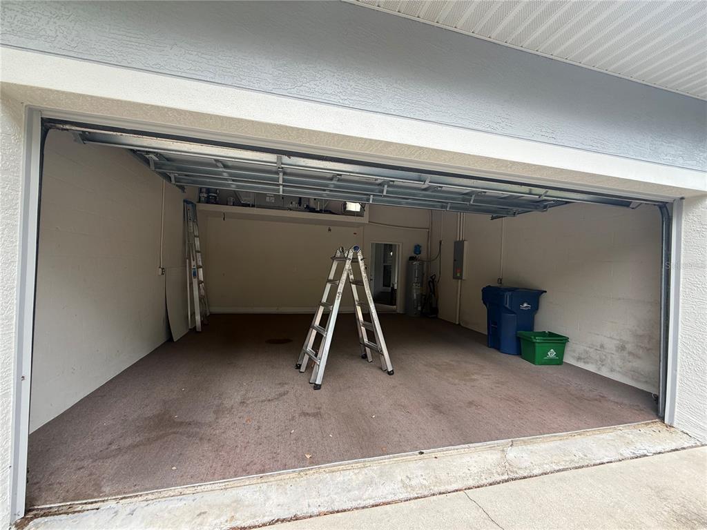 An empty garage with a concrete floor, a stepladder, and two plastic storage bins — 3132 CONNEMARA DRIVE, ORMOND BEACH, FL