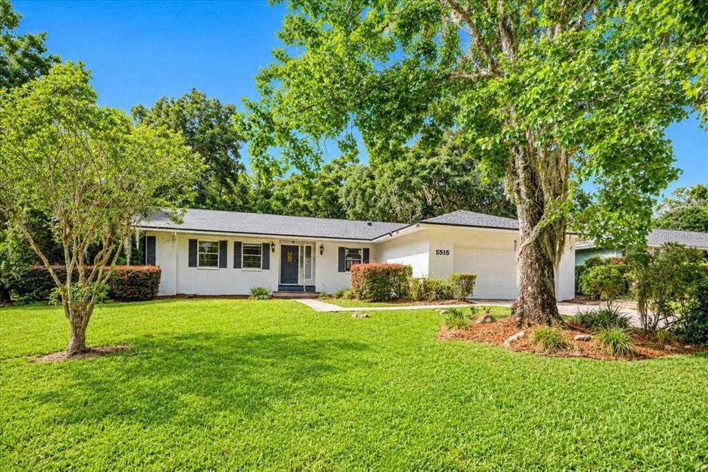 A single-story white house with a dark roof and a large front lawn — 5515 SW 35TH WAY, GAINESVILLE, FL