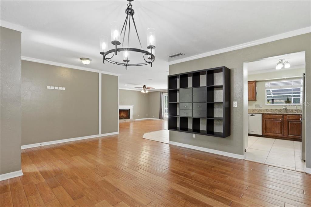 A dining area with a chandelier, wood floors, and a wall-mounted black shelving unit — 5515 SW 35TH WAY, GAINESVILLE, FL
