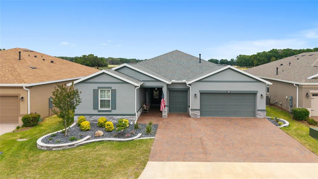 A single-story house with a gray exterior, stone accents, and a paved driveway — 4355 NW 53RD COURT, OCALA, FL