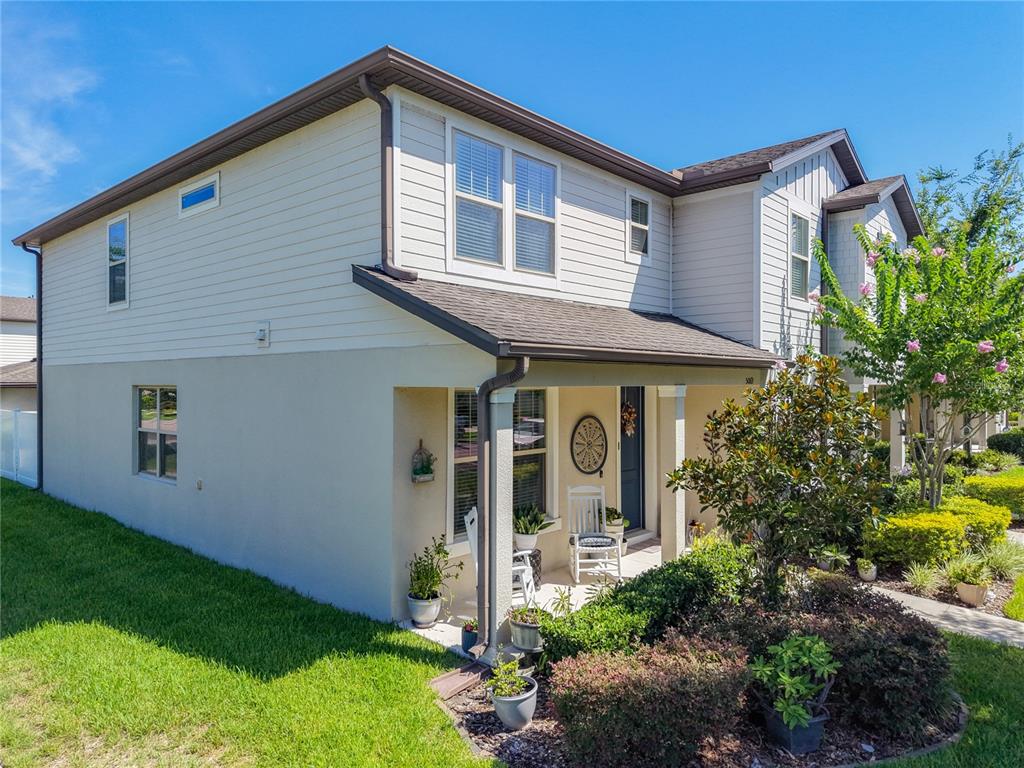 A two-story house features a covered front porch, light-colored siding, and a landscaped yard — 5069 CASPIAN STREET, ST CLOUD, FL