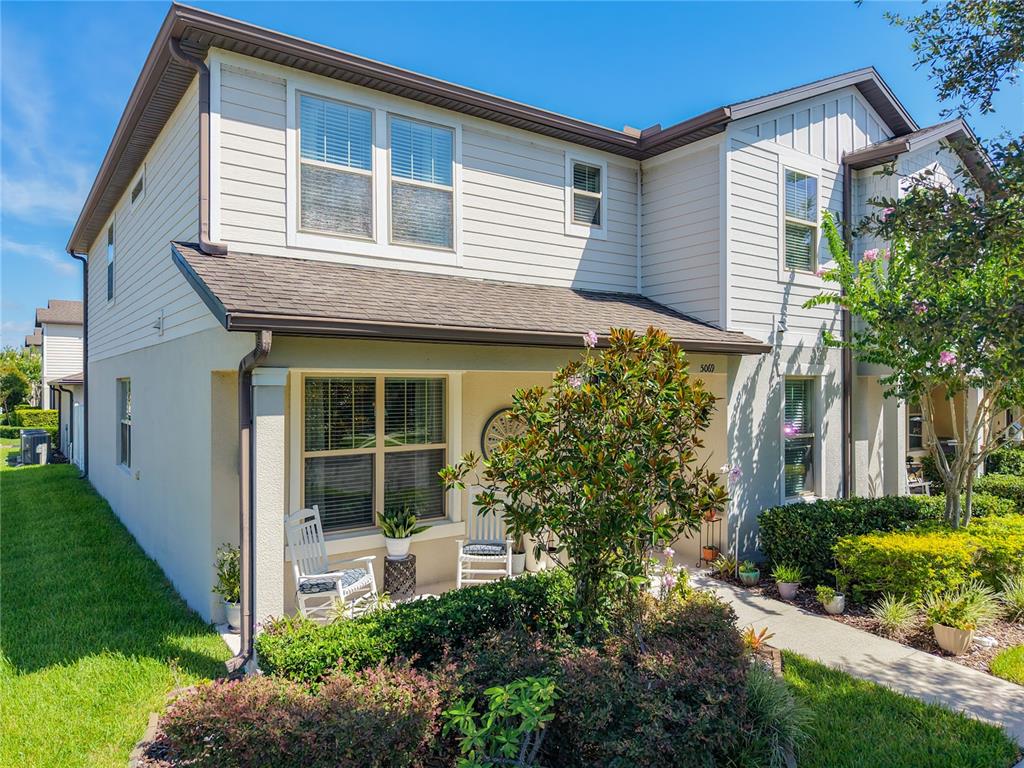 A two-story house with beige siding, a covered front porch, and a landscaped front yard — 5069 CASPIAN STREET, ST CLOUD, FL
