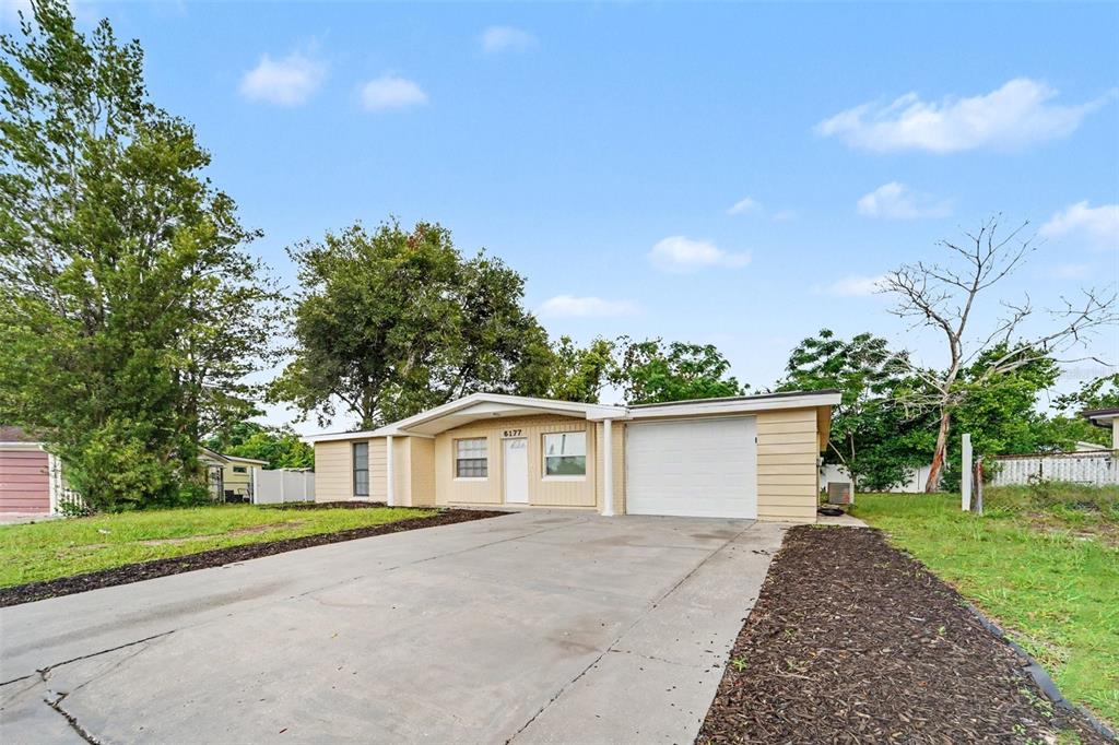 A single-story house with a beige exterior, a concrete driveway, and an attached garage — 6177 MAPLEWOOD DRIVE, NEW PORT RICHEY, FL