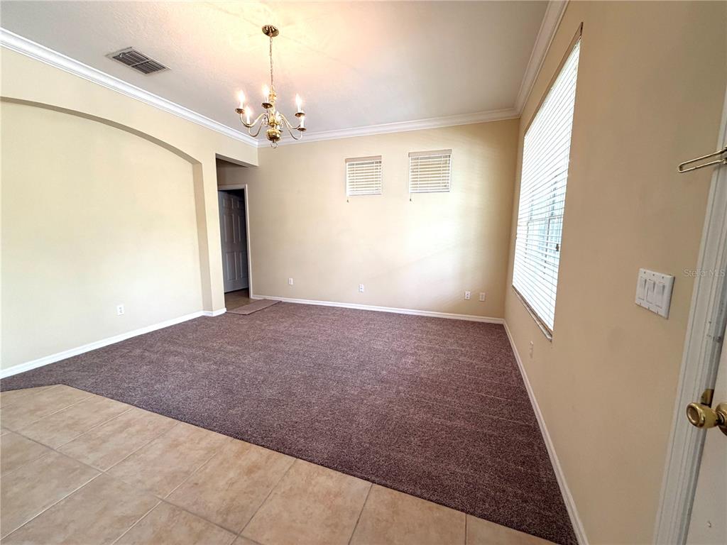 A carpeted living room features a chandelier, an arched wall cutout, and a large window — 14205 BRIDGEWATER CROSSINGS BOULEVARD, WINDERMERE, FL