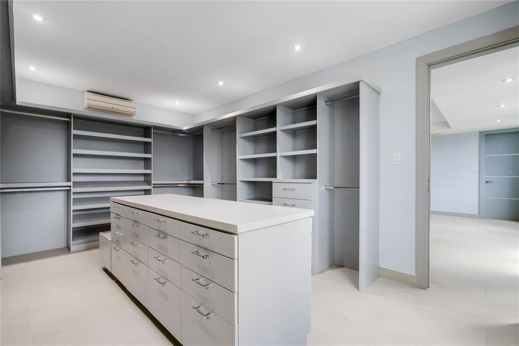 A walk-in closet features gray cabinetry, an island with drawers, and light-colored tile flooring — na TIVOLI, SAN JUAN, PR