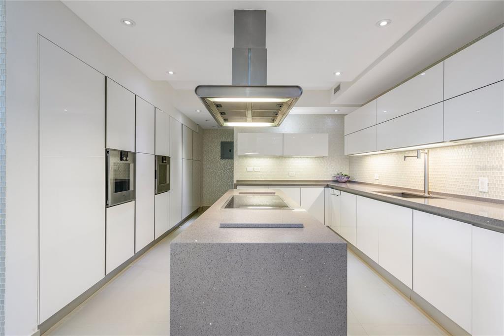 A modern kitchen features white cabinetry, gray quartz countertops, and a central island with hood — na TIVOLI, SAN JUAN, PR