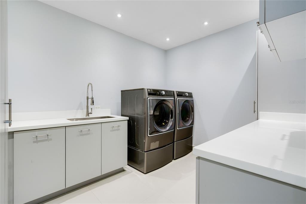 A laundry room with gray cabinets, white countertops, a sink, and dark gray appliances — na TIVOLI, SAN JUAN, PR