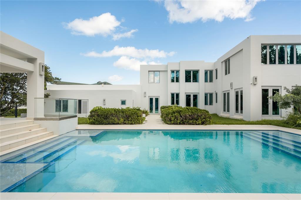 A modern white house with a swimming pool in the foreground under a blue sky — na TIVOLI, SAN JUAN, PR