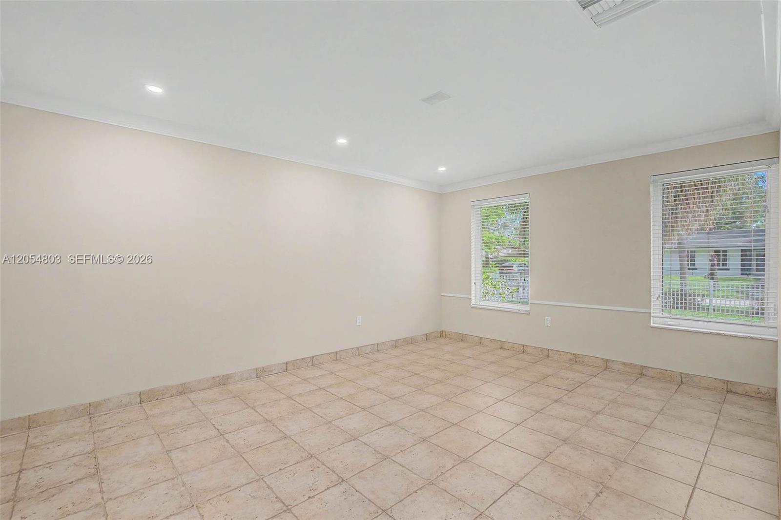 An empty room features beige walls, tile flooring, recessed lighting, and two windows with blinds — 10650 SW 77th Ct, Pinecrest FL 33156, PINECREST, FL