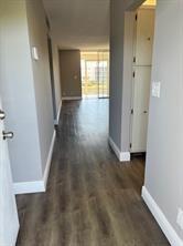 A hallway with wood-look flooring leads toward a bright living area with a glass door — 1025 SE 3rd Avenue # 303, Dania Beach FL 33004, DANIA BEACH, FL