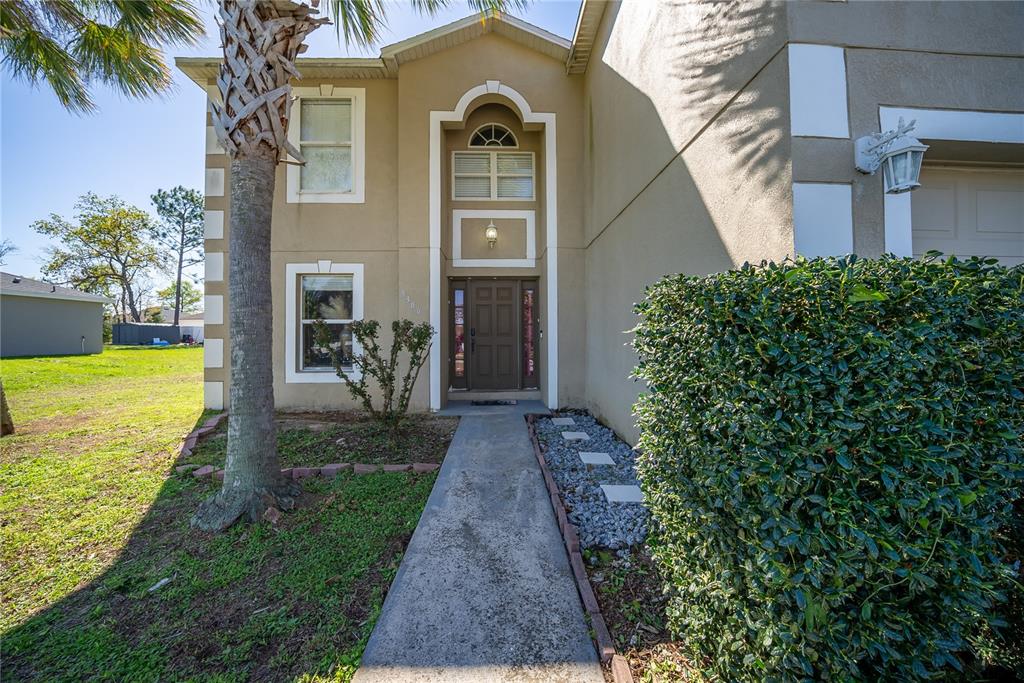 A two-story house exterior features a concrete walkway, a palm tree, and a large bush — 5306 SW 115TH STREET ROAD, OCALA, FL