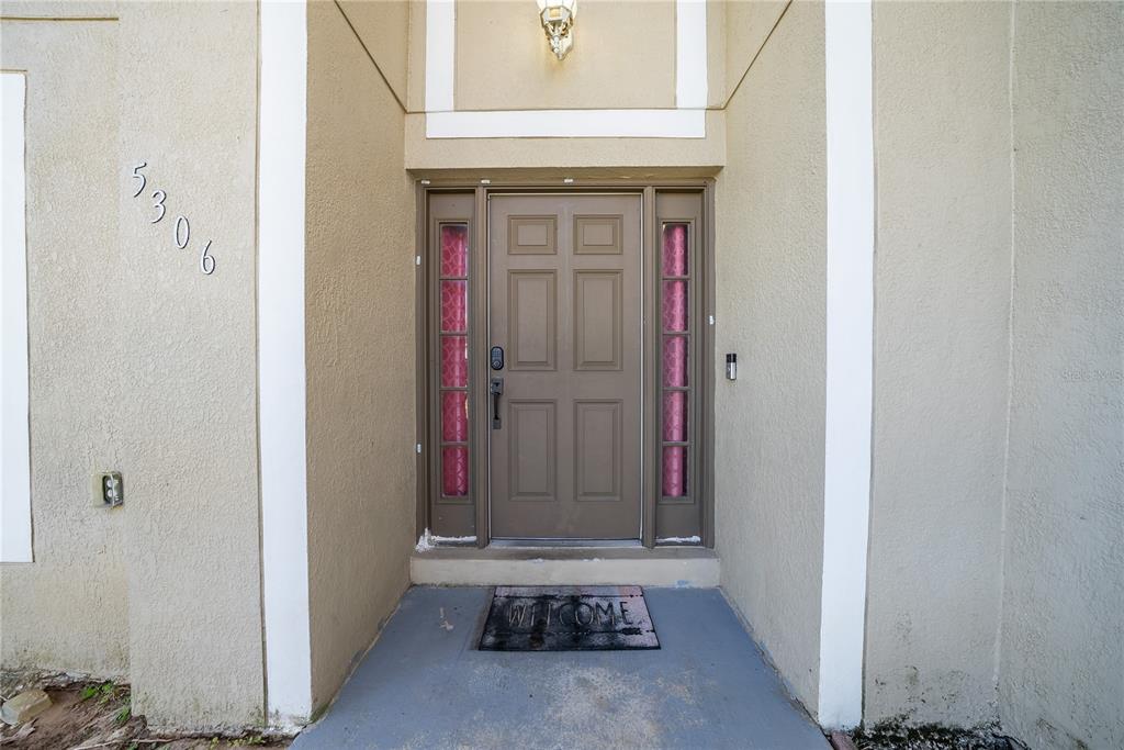A front entrance features a tan door with side windows and a welcome mat — 5306 SW 115TH STREET ROAD, OCALA, FL