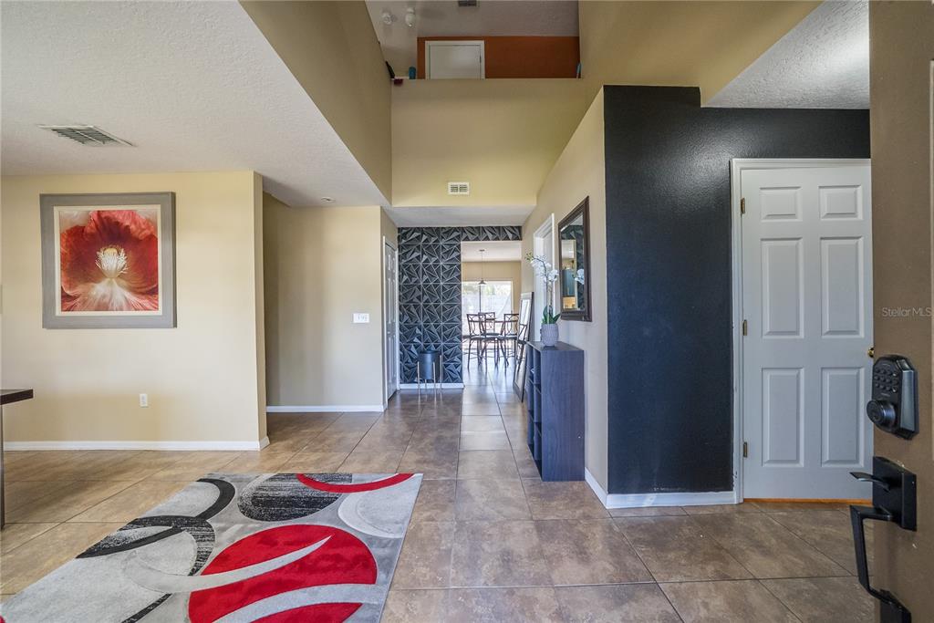 An entryway features tile flooring, a high ceiling, and a black accent wall with geometric tiles — 5306 SW 115TH STREET ROAD, OCALA, FL