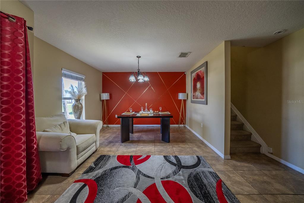 A dining room features a red accent wall with gold trim and a patterned rug — 5306 SW 115TH STREET ROAD, OCALA, FL