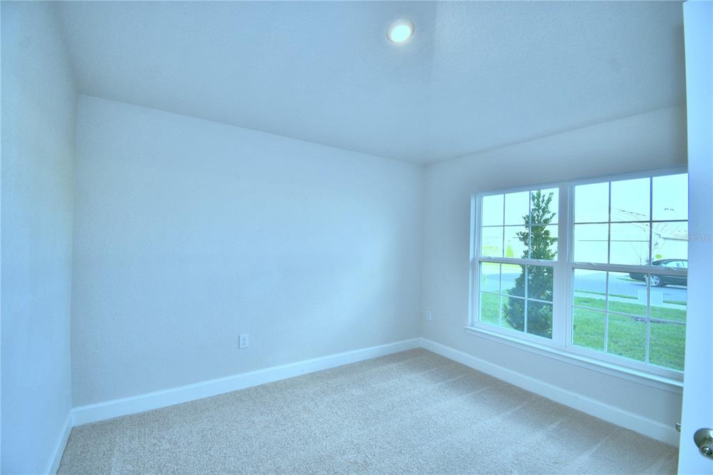 A hallway with gray tile flooring leads to a glass-paneled door at the far end — 1249 TAGLIAMENTO LANE, HAINES CITY, FL