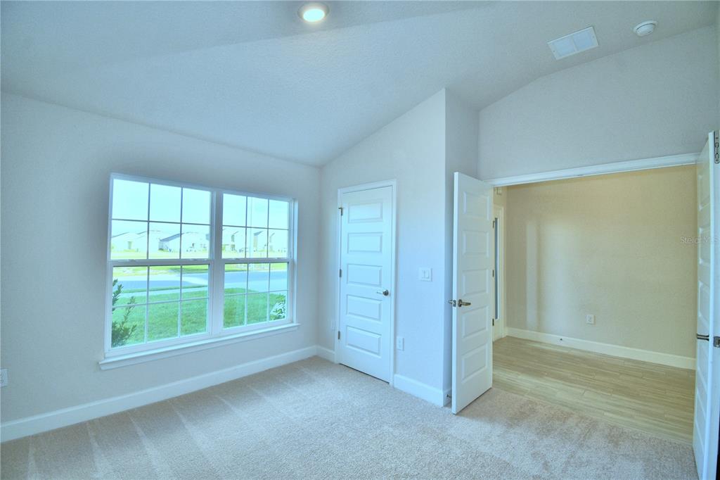 A hallway with gray tile flooring leads to a glass-paned door in a bright room — 1249 TAGLIAMENTO LANE, HAINES CITY, FL