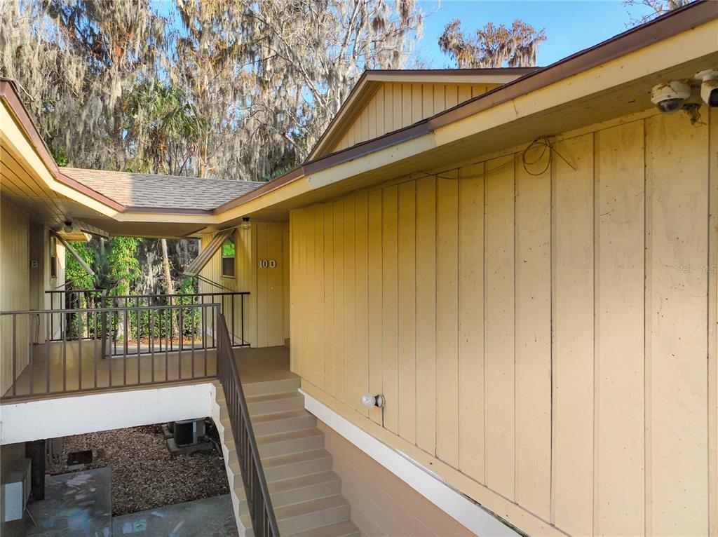 An exterior view of a yellow building with an outdoor staircase leading to unit 10D — 130 JASMINE WOODS COURT UNIT 10D, DELTONA, FL