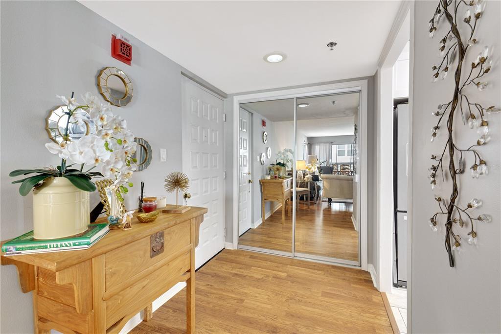 An entryway features a wooden console table, mirrored closet doors, and light wood flooring — 204 QUAYSIDE CIRCLE UNIT 201, MAITLAND, FL