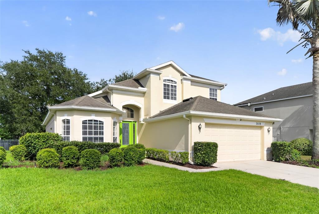 A two-story suburban house with a beige stucco exterior, a green front door, and garage — 3519 MCCORMICK WOODS DRIVE, OCOEE, FL