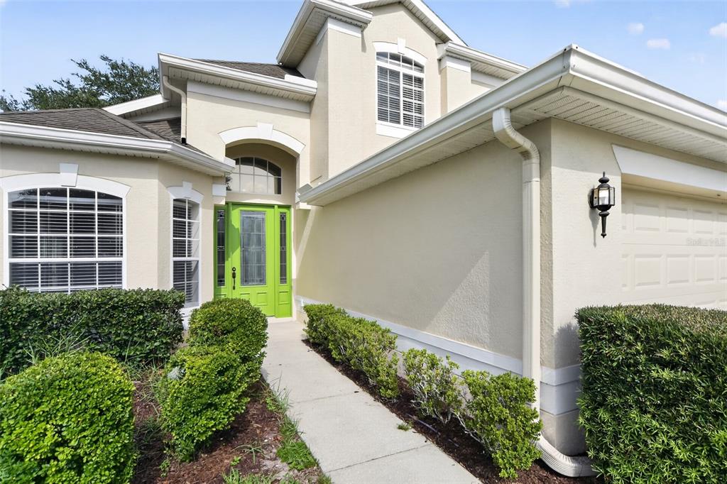 A beige two-story house features a bright green front door and a concrete walkway — 3519 MCCORMICK WOODS DRIVE, OCOEE, FL