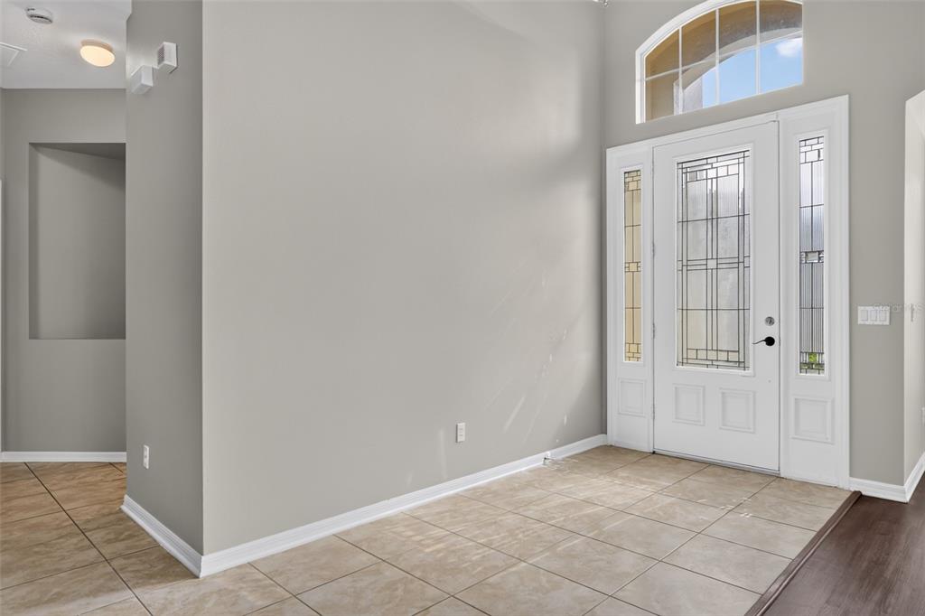 An entryway with beige tile flooring, a white front door with glass panels, and high ceilings — 3519 MCCORMICK WOODS DRIVE, OCOEE, FL