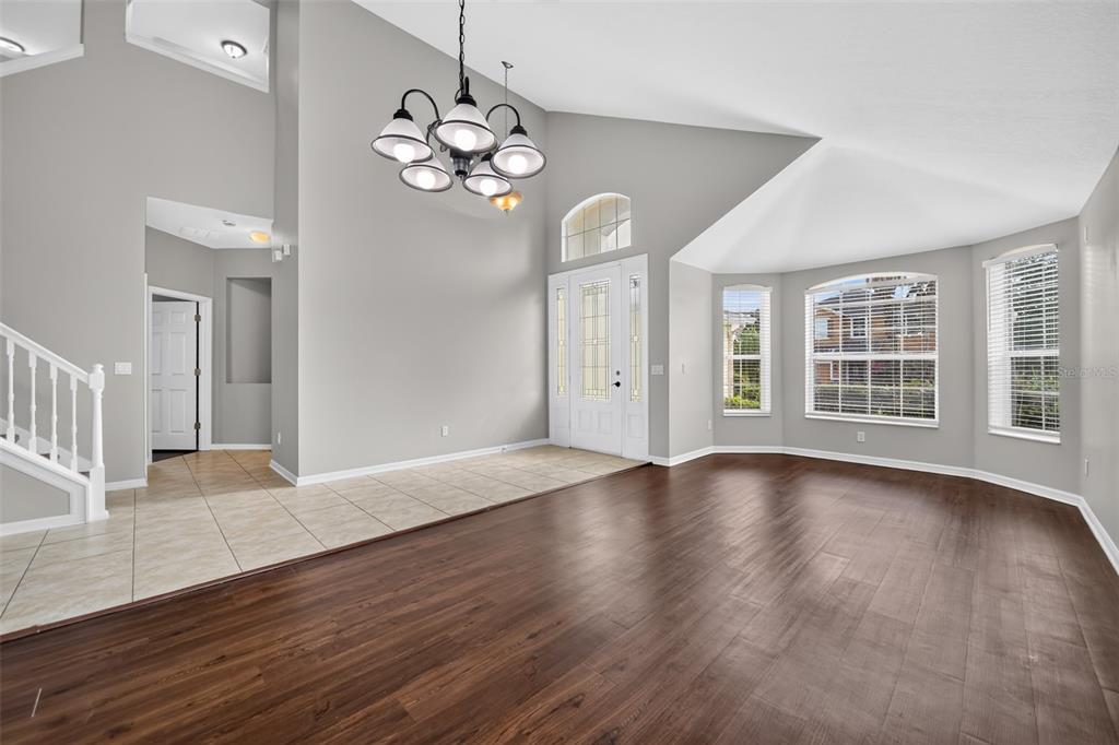 A spacious living room features high ceilings, dark wood flooring, tile entry, and large windows — 3519 MCCORMICK WOODS DRIVE, OCOEE, FL