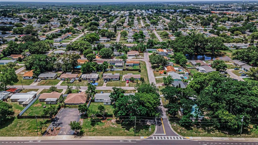 An aerial view shows a residential neighborhood with houses, trees, and a small pond — SR 54, NEW PORT RICHEY, FL