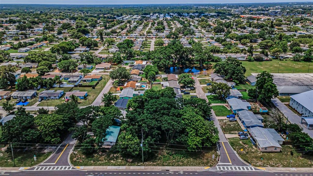 An aerial view shows a residential neighborhood with houses, trees, and a small pond — SR 54, NEW PORT RICHEY, FL