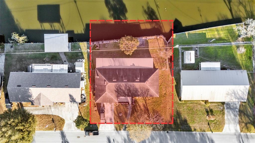 An aerial view shows a house with a brown roof situated on a waterfront lot — 5717 LAKE GROVE DRIVE, LAKELAND, FL