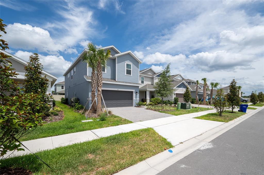 A two-story blue house with a gray garage and a paved driveway under a cloudy sky — 1029 LADYFISH TRAIL, ST CLOUD, FL