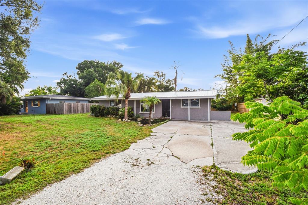 A single-story gray house with a metal roof and a cracked concrete driveway — 5917 OLIVE AVENUE, SARASOTA, FL