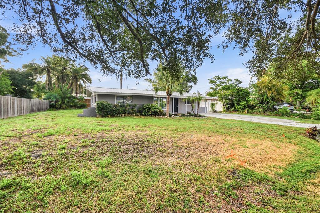 A single-story gray house with a metal roof sits on a large, grassy lot — 5917 OLIVE AVENUE, SARASOTA, FL