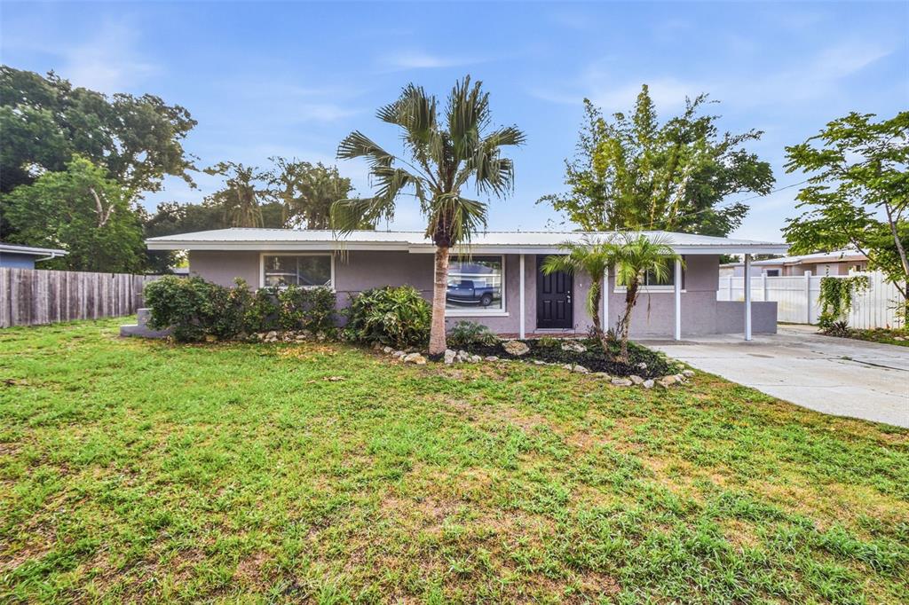 A single-story gray house with a metal roof, palm trees, and a concrete driveway — 5917 OLIVE AVENUE, SARASOTA, FL