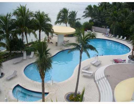 An elevated view of a curved swimming pool and hot tub surrounded by palm trees — 1330 West Ave # 2212, Miami Beach FL 33139, MIAMI BEACH, FL