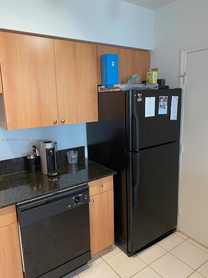 A kitchen features light wood cabinets, black appliances, and dark granite countertops — 1330 West Ave # 2212, Miami Beach FL 33139, MIAMI BEACH, FL