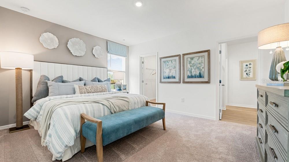 A bedroom features a bed with a blue bench, wall art, and a dresser — 5454 ISLA SAONA DRIVE, KISSIMMEE, FL