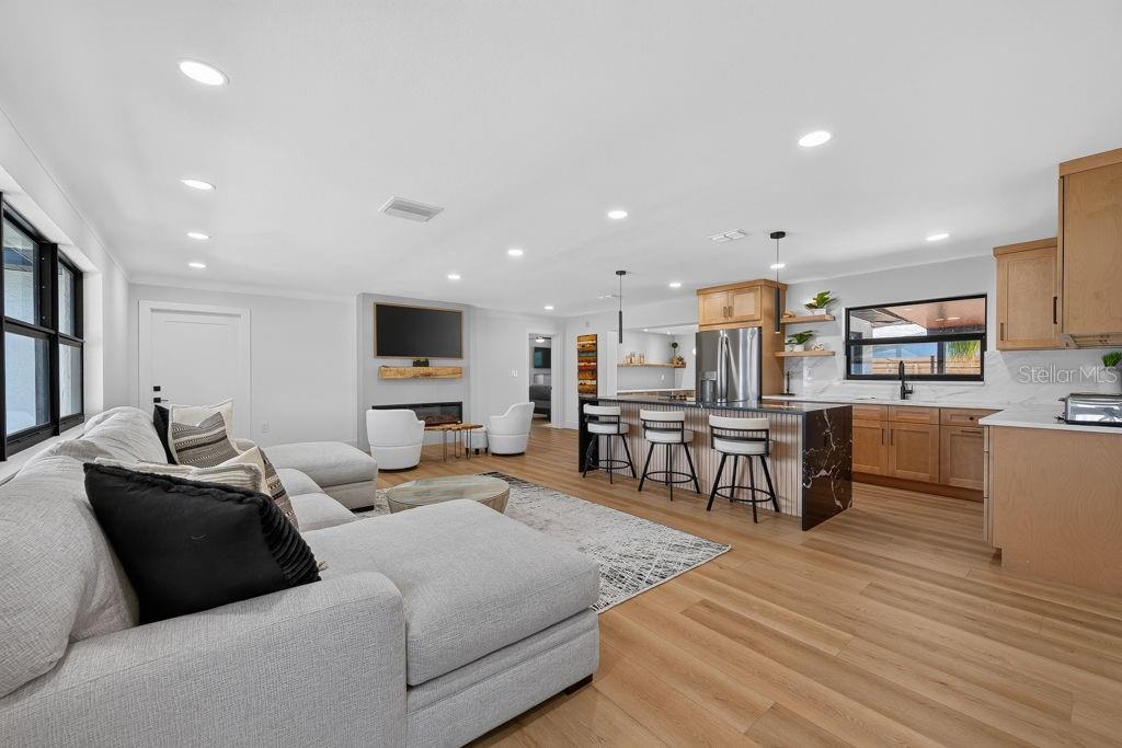 An open-concept living room and kitchen featuring light wood flooring, a sectional, and island seating — 6196 44TH AVENUE N, ST PETERSBURG, FL