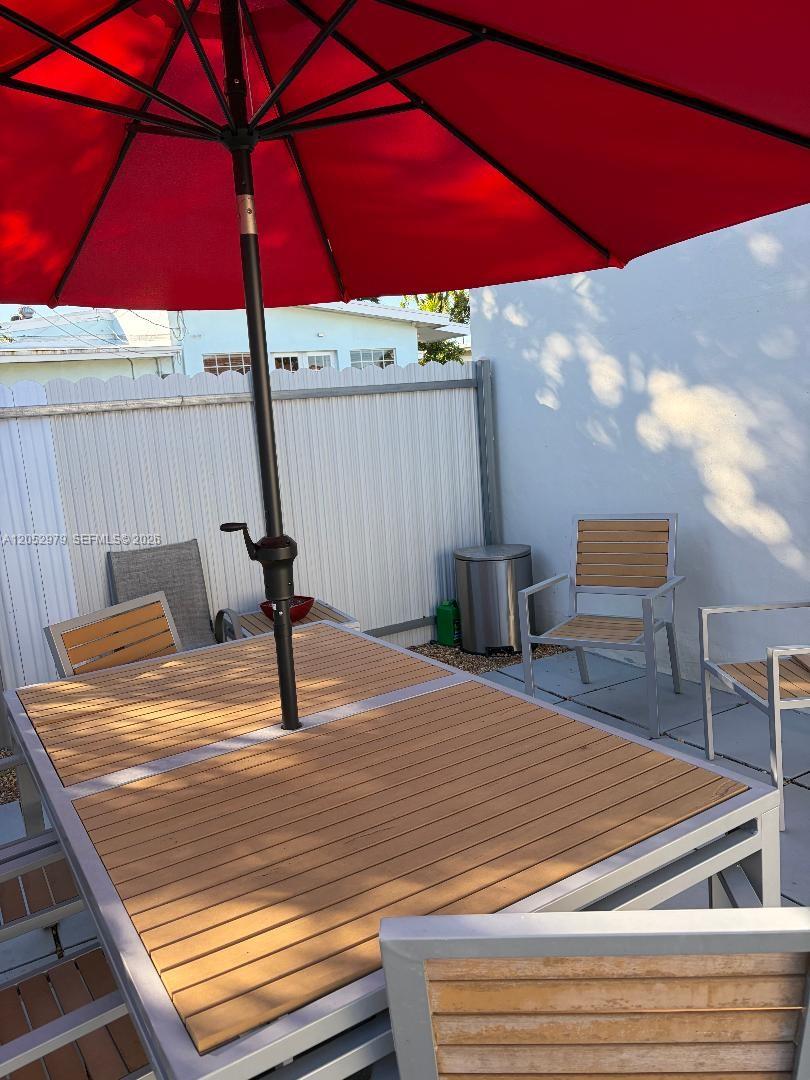A patio features a wooden dining table with a red umbrella and matching chairs — MIAMI, FL