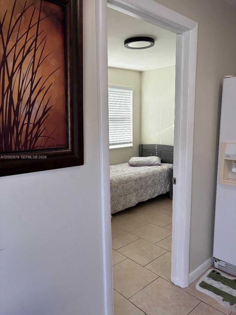 A view through a doorway shows a bedroom with a bed and tiled flooring — MIAMI, FL