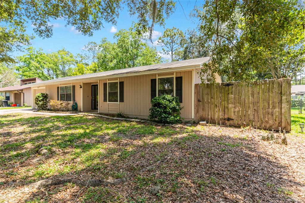 A single-story house with beige vertical siding and a wooden privacy fence — 2541 NW 52ND PLACE, GAINESVILLE, FL