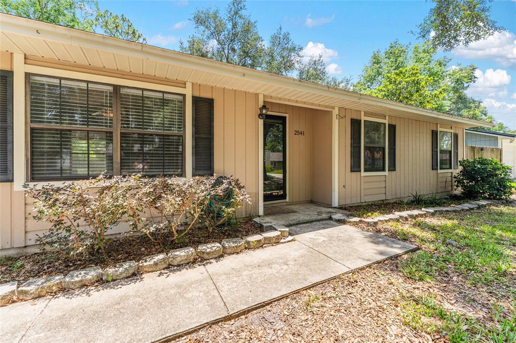 A single-story house with tan vertical siding, a concrete walkway, and a front entrance — 2541 NW 52ND PLACE, GAINESVILLE, FL