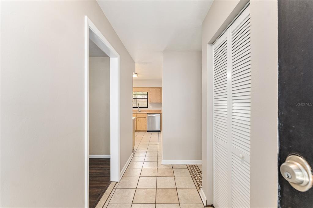 A hallway with tiled flooring leads to a kitchen with wooden cabinets and stainless appliances — 2541 NW 52ND PLACE, GAINESVILLE, FL
