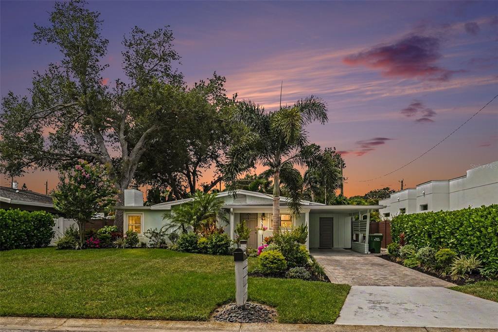 A single-story house with a paved driveway, palm tree, and large oak tree at sunset — 2344 TEMPLE STREET, SARASOTA, FL