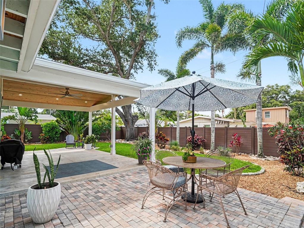 A patio features a covered seating area, a dining set with an umbrella, and landscaping — 2344 TEMPLE STREET, SARASOTA, FL