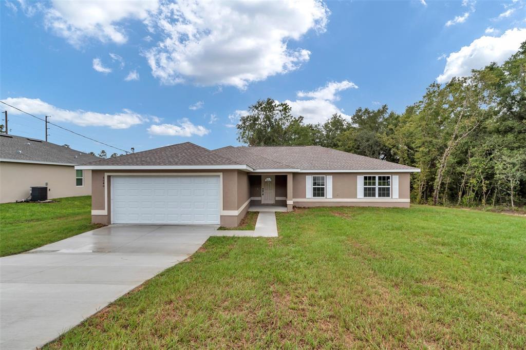 A single-story house with a tan stucco exterior, white garage door, and a concrete driveway — 6781 NW 47TH AVENUE, OCALA, FL