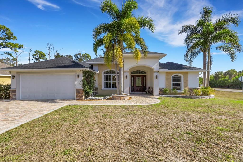 A single-story house with a paved driveway, two palm trees, and a stone-accented exterior — 13471 EISENHOWER DRIVE, PORT CHARLOTTE, FL