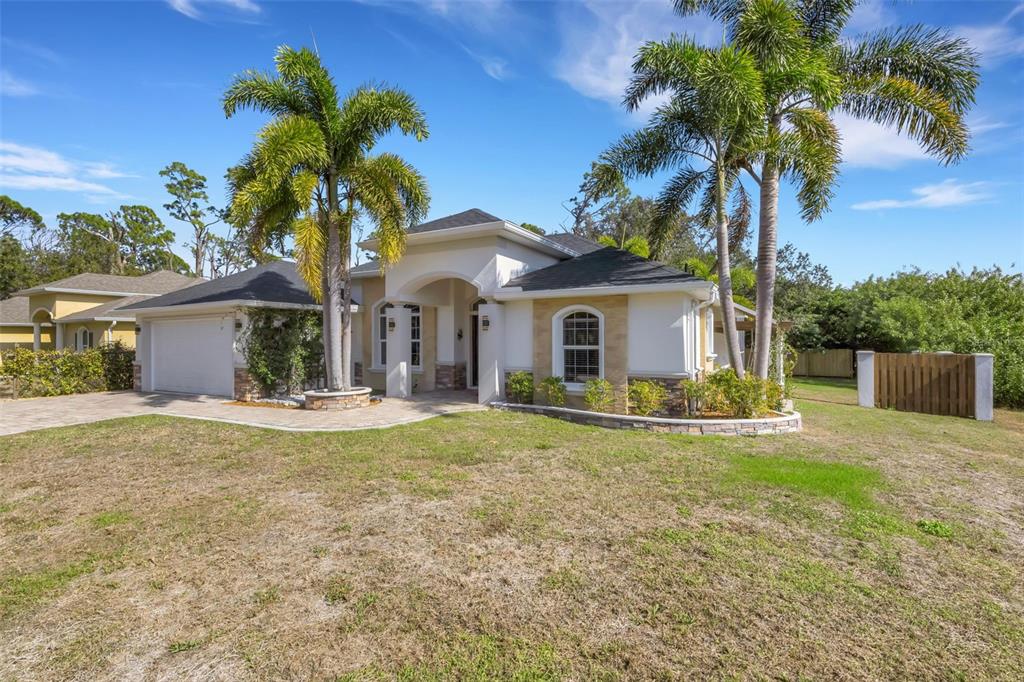 A single-story house with a paved driveway, palm trees, and a stone-accented exterior — 13471 EISENHOWER DRIVE, PORT CHARLOTTE, FL
