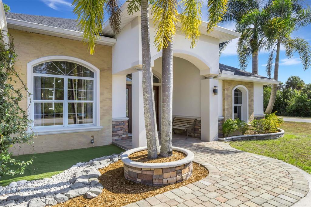 A paved walkway leads to the covered entrance of a house with stone accents — 13471 EISENHOWER DRIVE, PORT CHARLOTTE, FL